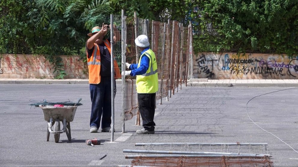 Trabajadores instalan un vallado.