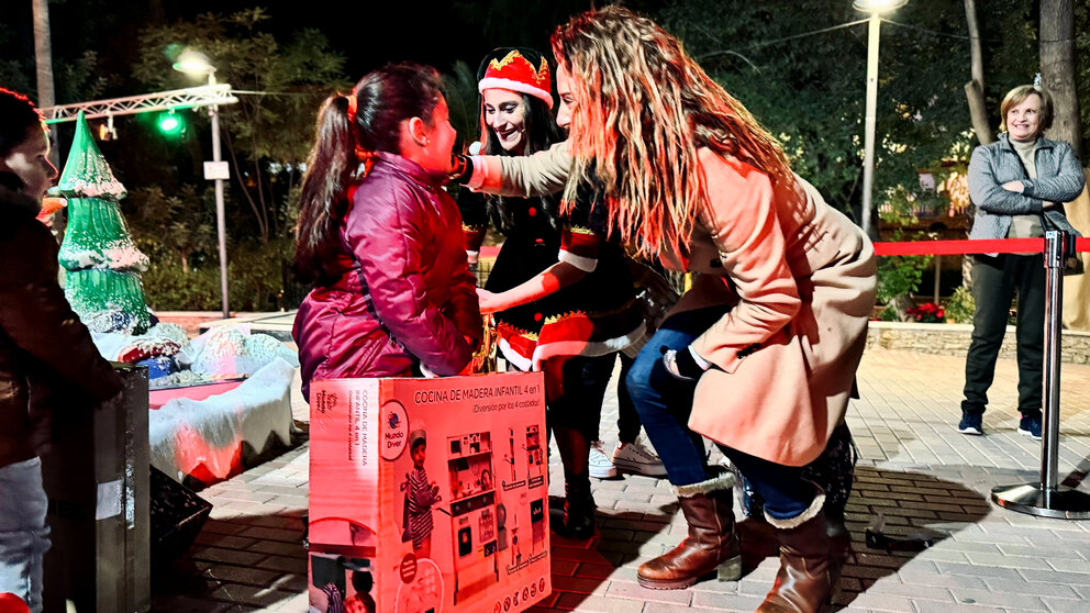 una niña recoge su regalo de la Estrella de los Deseos en presencia de la alcaldesa