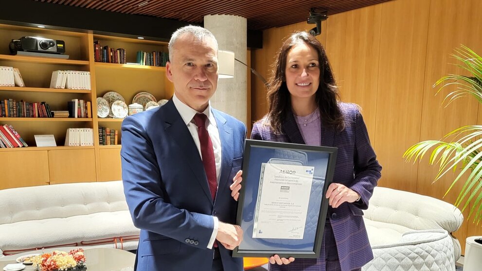 El CEO de Aenor, Rafael García Meiro, entrega el certificado a Olga Abad, directora de Banca de Empresas e Instituciones de Santander España. (Banco Santander)