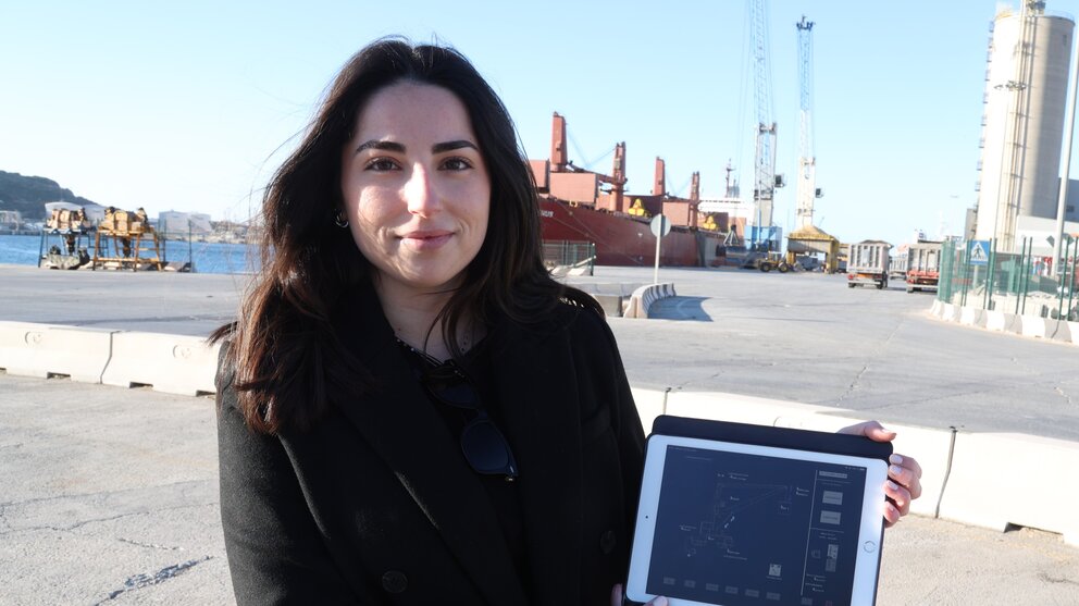 María Segado, en la dársena de Escombreras, mostrando un esquema de su trabajo para el modelo de grúas que operan al fondo. (UPCT)