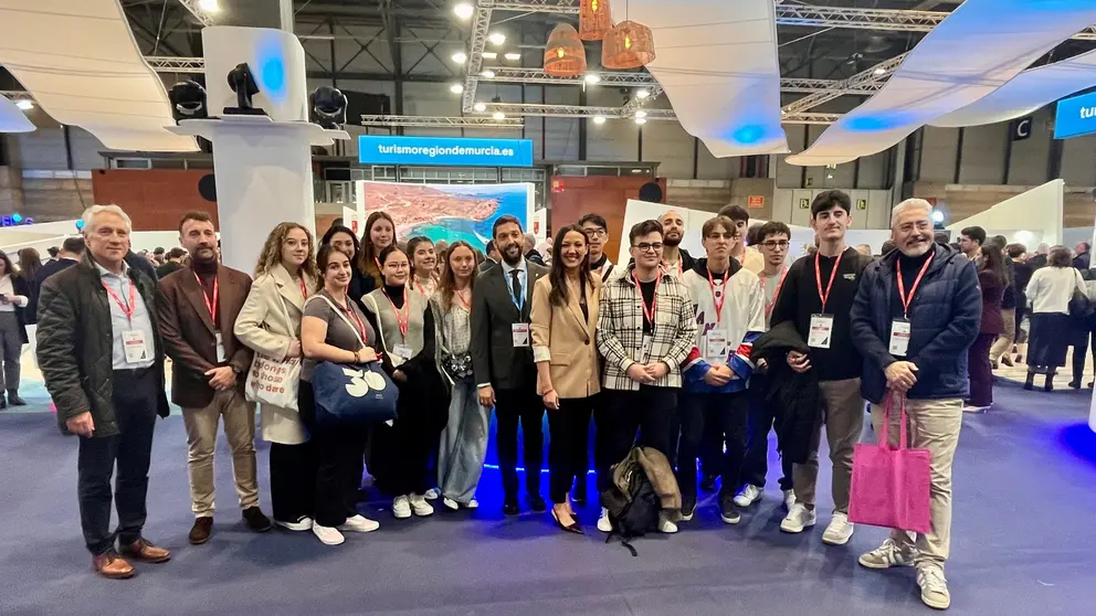 La consejera Carmen Conesa y el director del Instituto de Turismo, con un grupo de estudiantes de Turismo ante el estand de la Región en Fitur. (CARM)