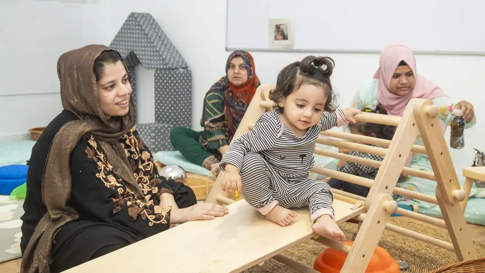 Una madre mira a su hija, subida a un parque de aprendizaje Pikler. (Fundación 'la Caixa' / Adrián Quiroga)